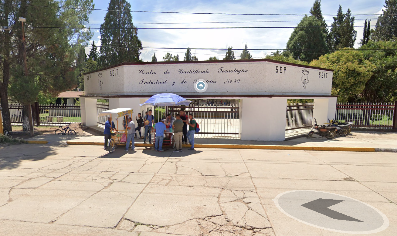 Fotografía en la que se muestra la entrada del plantel, conformada por muros blancos intercalados con rejas rojas. La reja de en medio es la que da acceso al plantel y arriba de ella hay un muro blanco que dice CENTRO DE BACHILLERATO TECNOLÓGICO INDUSTRIAL Y DE SERVICIOS NÚMERO 42.